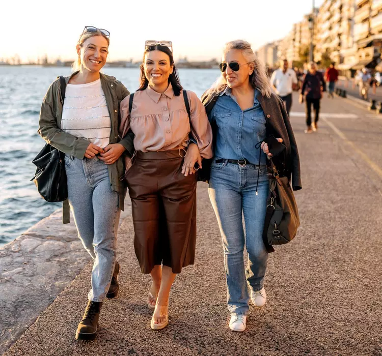 Female friends on holiday walking by the sea in the city