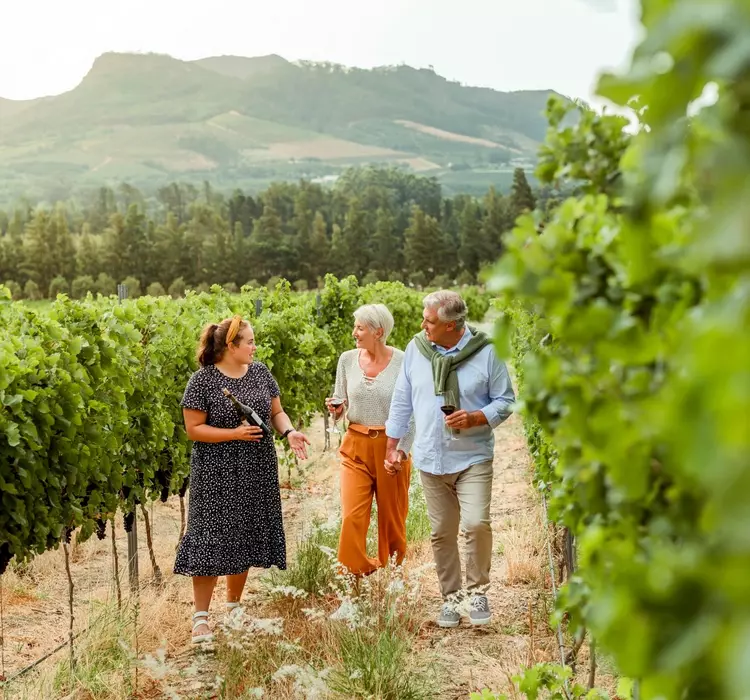 Couple getting tour of a vineyard with woman farmer during vacation