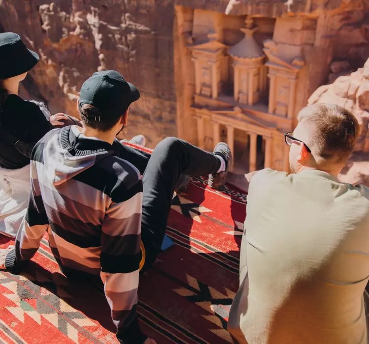 Petra, Jordan Group sitting on the top of the cliff looking at the famous old Petra town gates hidden in the canyon in Jordan, the Middle East