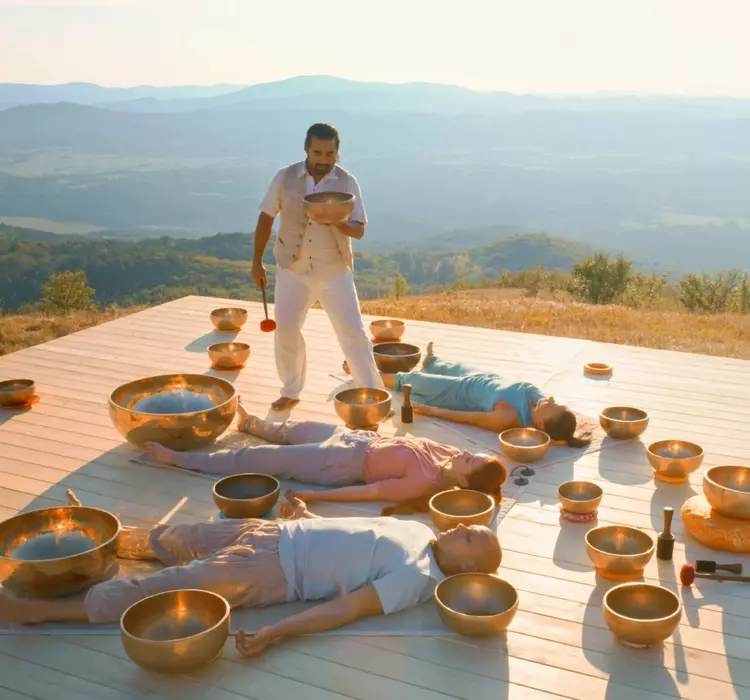 Male therapist playing ring gong while performing music therapy during sunset