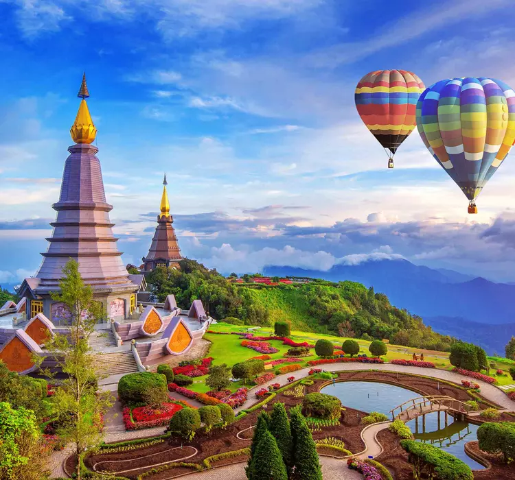 Hot air balloons over mountain landscape with pagodas and rice paddies