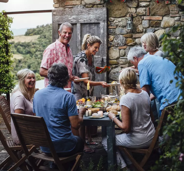 A group of people eat dinner at an outdoor dining table in Italy.