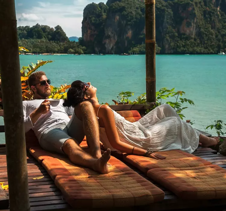 Couple relaxing together in a sea-side bungalow, surrounded by lush greenery.