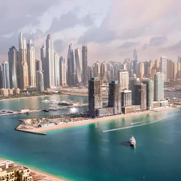 Skyscrapers, Dubai marina in the sunny day with front line of beach hotels and blue water of Persian gulf