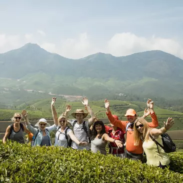 A group of travellers posing for a photo in the plantation hills outside Kerala, India.
