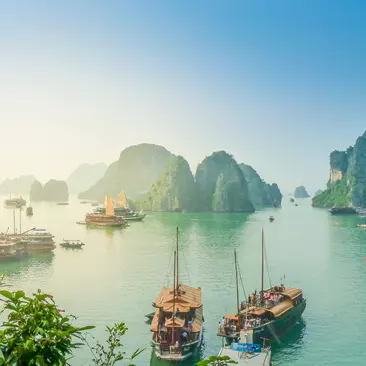 View of junker boats on Halong Bay in Vietnam with karsts in the background.