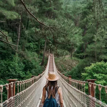 A woman crossing a rope bridge on vacation