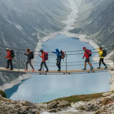 A group of travellers walking across a suspension bridge above a fjord