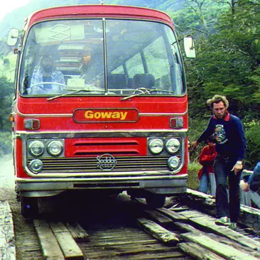 An old tour bus crosses a bridge in the 1970s in Latin America