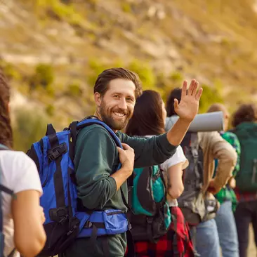 A backpacker smiles while hiking through a destination with several others
