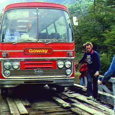 An old tour bus crosses a bridge in the 1970s in Latin America
