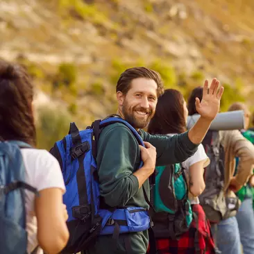 A backpacker smiles while hiking through a destination with several others