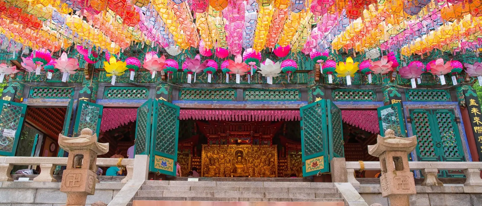 A temple entrance adorned with colorful lanterns hanging from above, creating a vibrant and festive atmosphere.