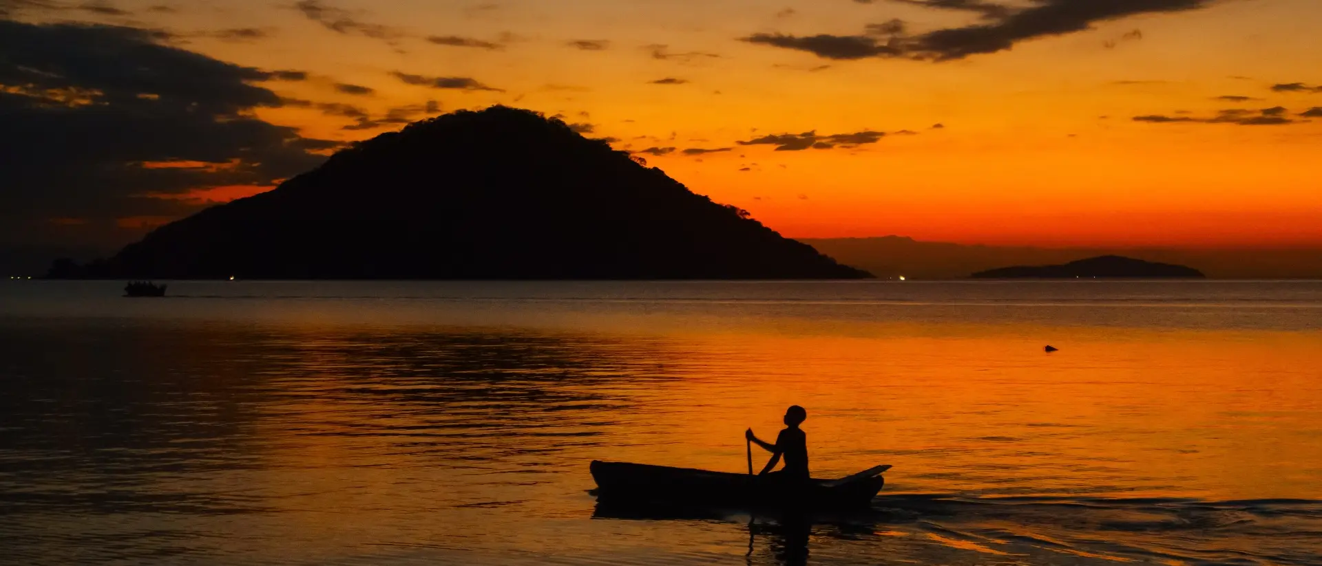 Fisherman on boat at sunset in lake