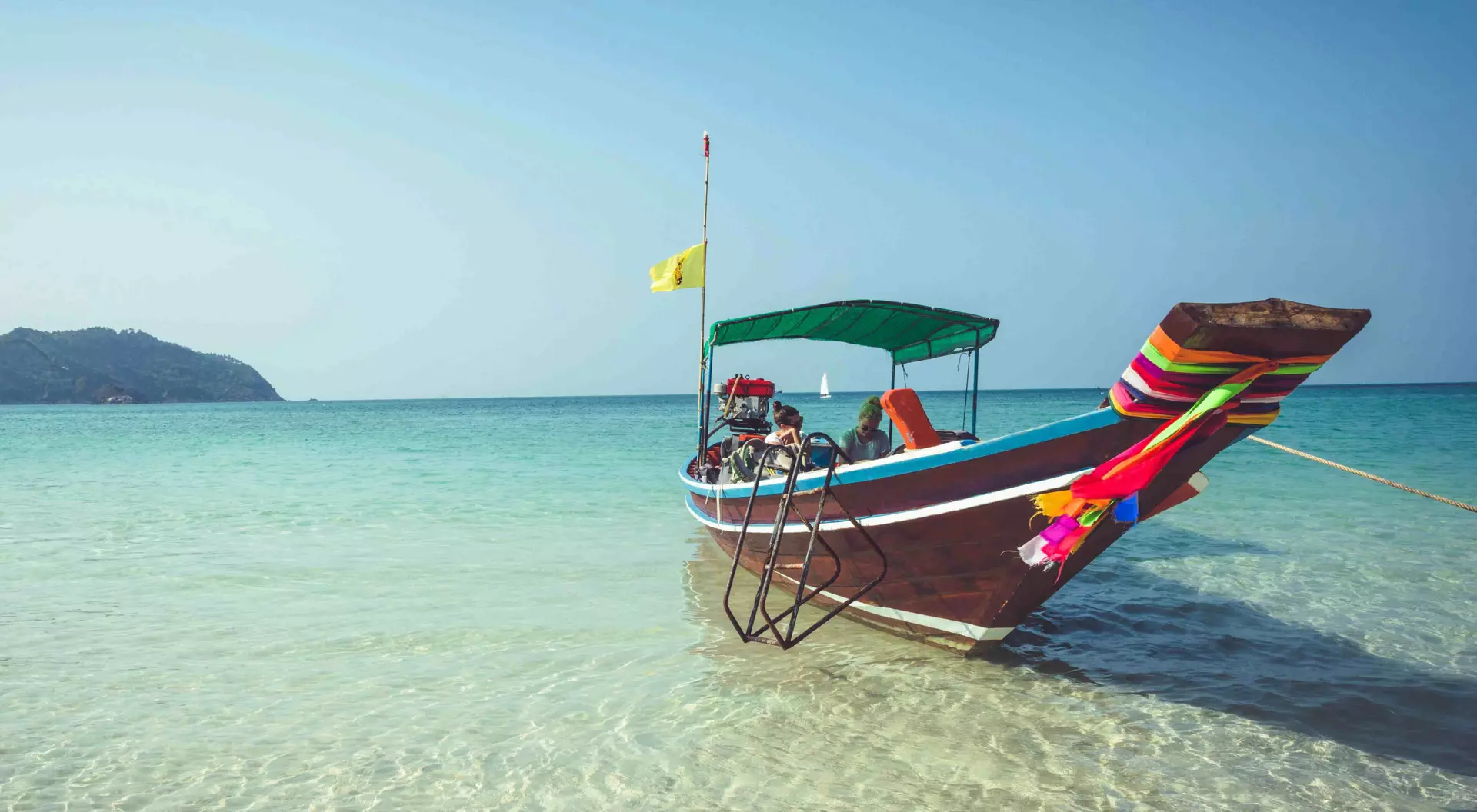 A boat is anchored at the beach, over crystal clear waters