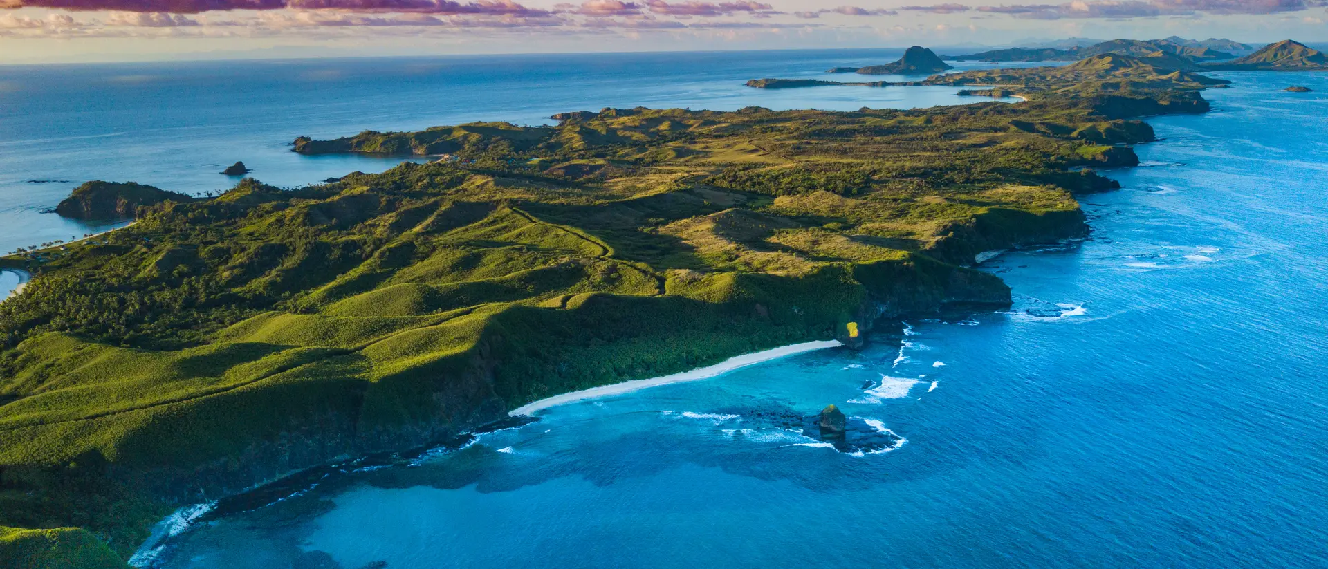 Aerial view of a Fiji island with bright green foliage and sunset sky