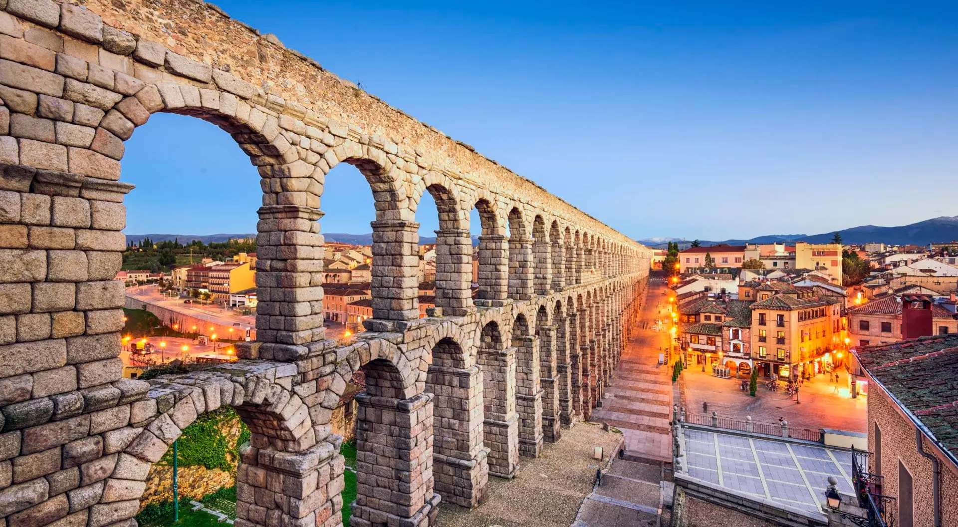 Ancient Roman aqueduct cutting through ancient village at twilight.