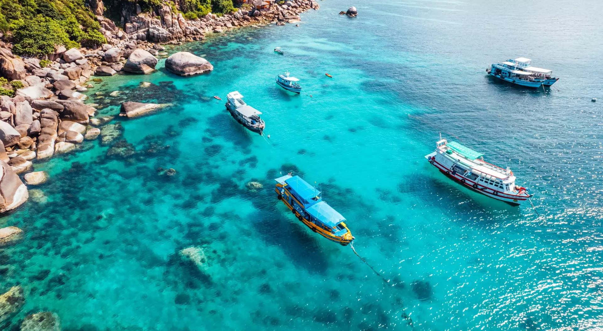 Boats and crystal clear waters at the bay dive site from above