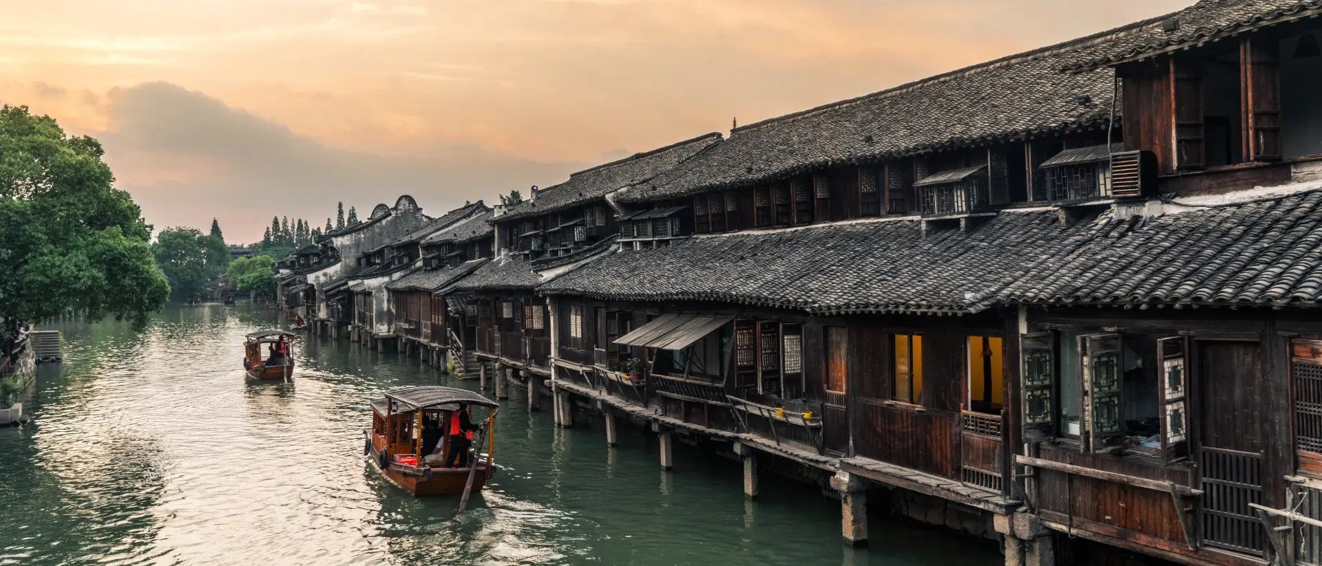 Wuzhan Boats pass by ancient houses along river in Wuzhen, a historic scenic town