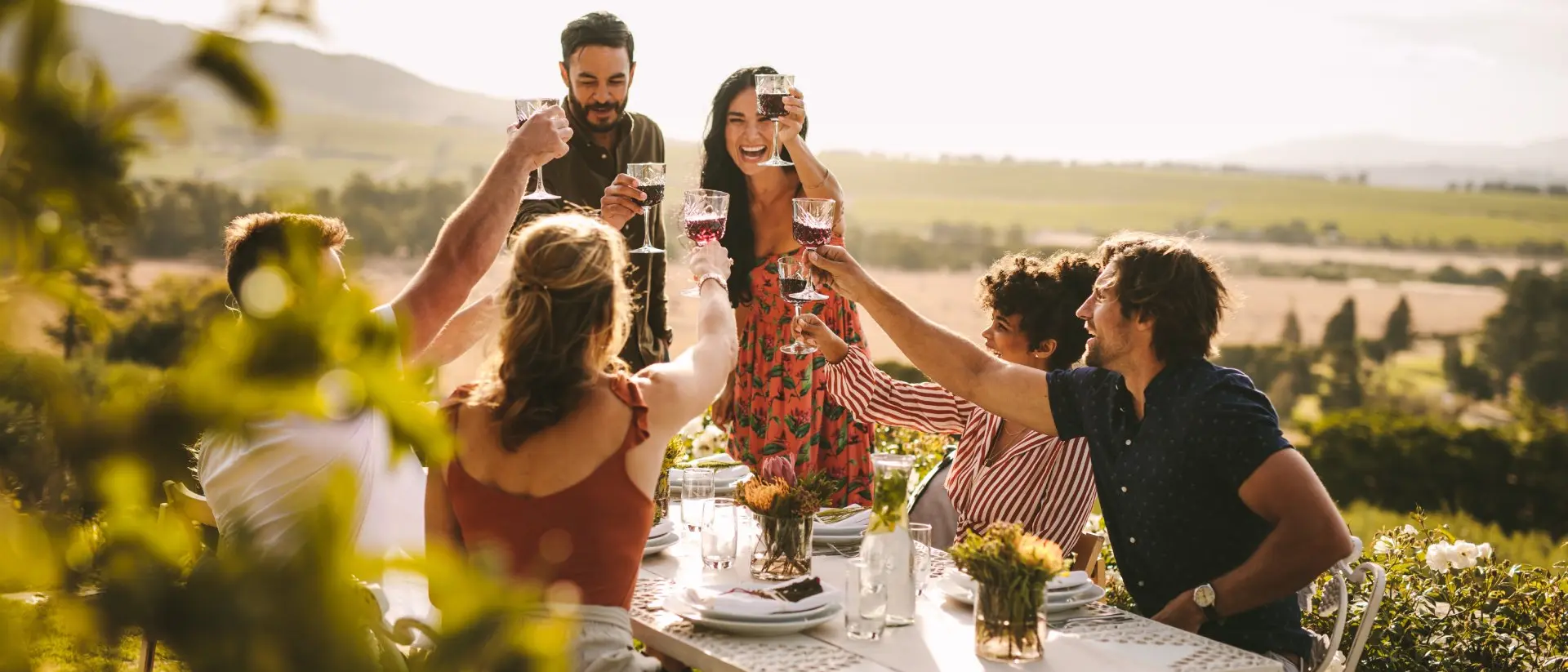 Group of friends toasting wine and enjoying dinner outdoors