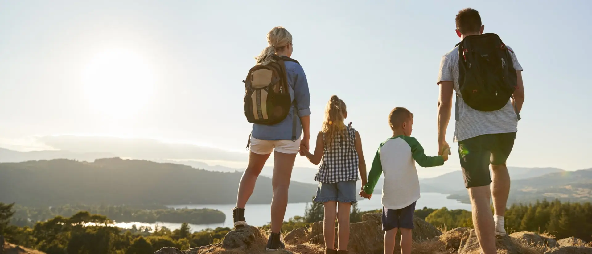 Rear View Of Family Standing At Top Of Hill On Hike Through Countryside In Lake District UK