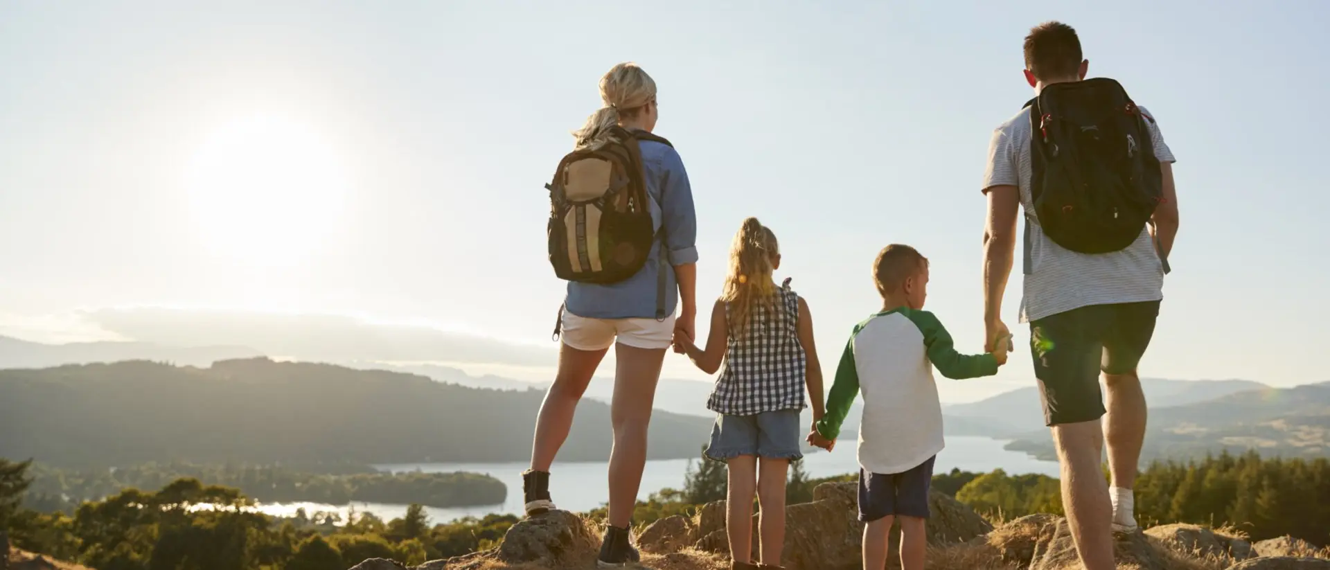 Rear View Of Family Standing At Top Of Hill On Hike Through Countryside In Lake District UK
