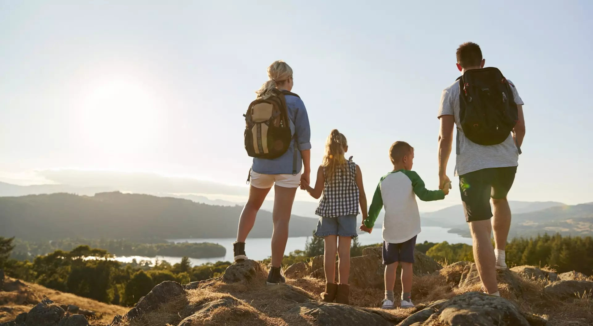 Rear View Of Family Standing At Top Of Hill On Hike Through Countryside In Lake District UK