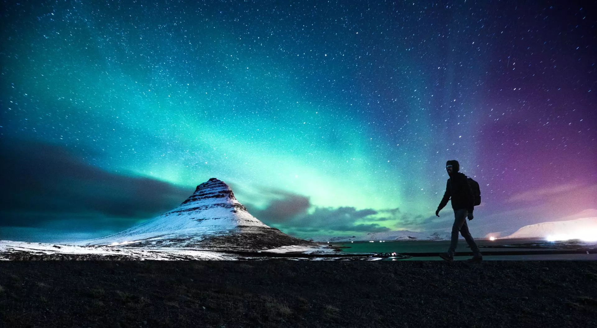 Solo traveler walking in front of an awesome Northern Lights in Mount Kirkjufell Iceland.