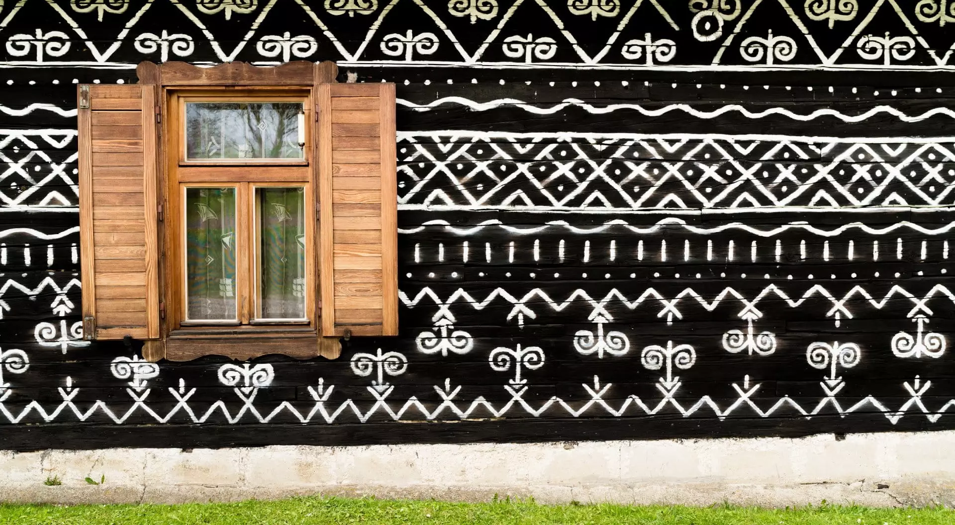 Cicmany, Slovakia Wooden window on the White and black pattern ornament painting on the dark wood wall in Slovakian old village Cicmany