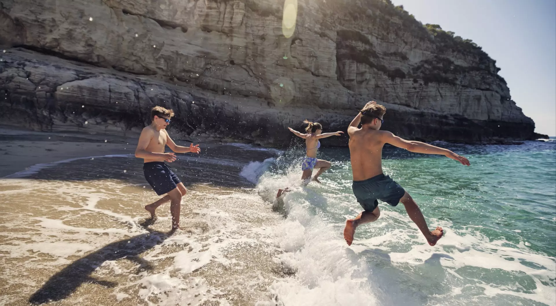 A bunch of happy teenagers running into the surf in Italy