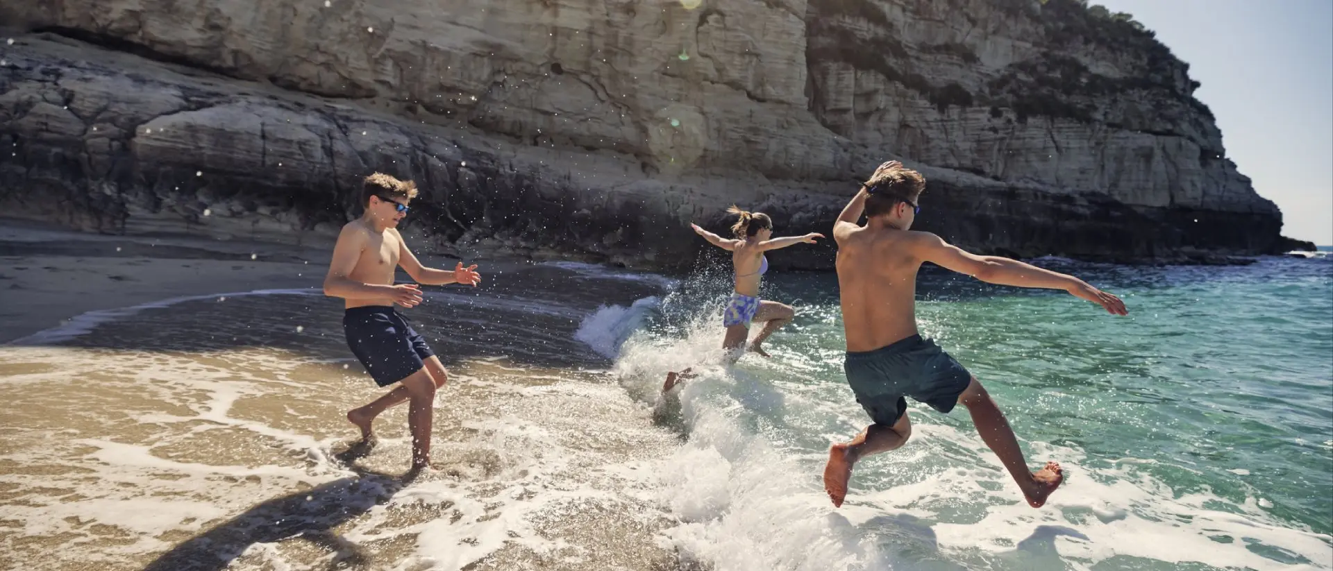 A bunch of happy teenagers running into the surf in Italy