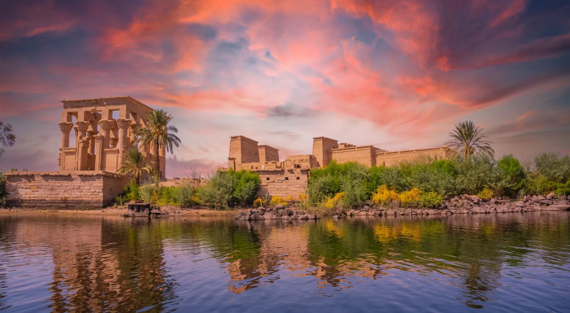 Incredible orange sunrise at the temple of Philae, a Greco-Roman construction seen from the Nile river, a temple dedicated to Isis, goddess of love