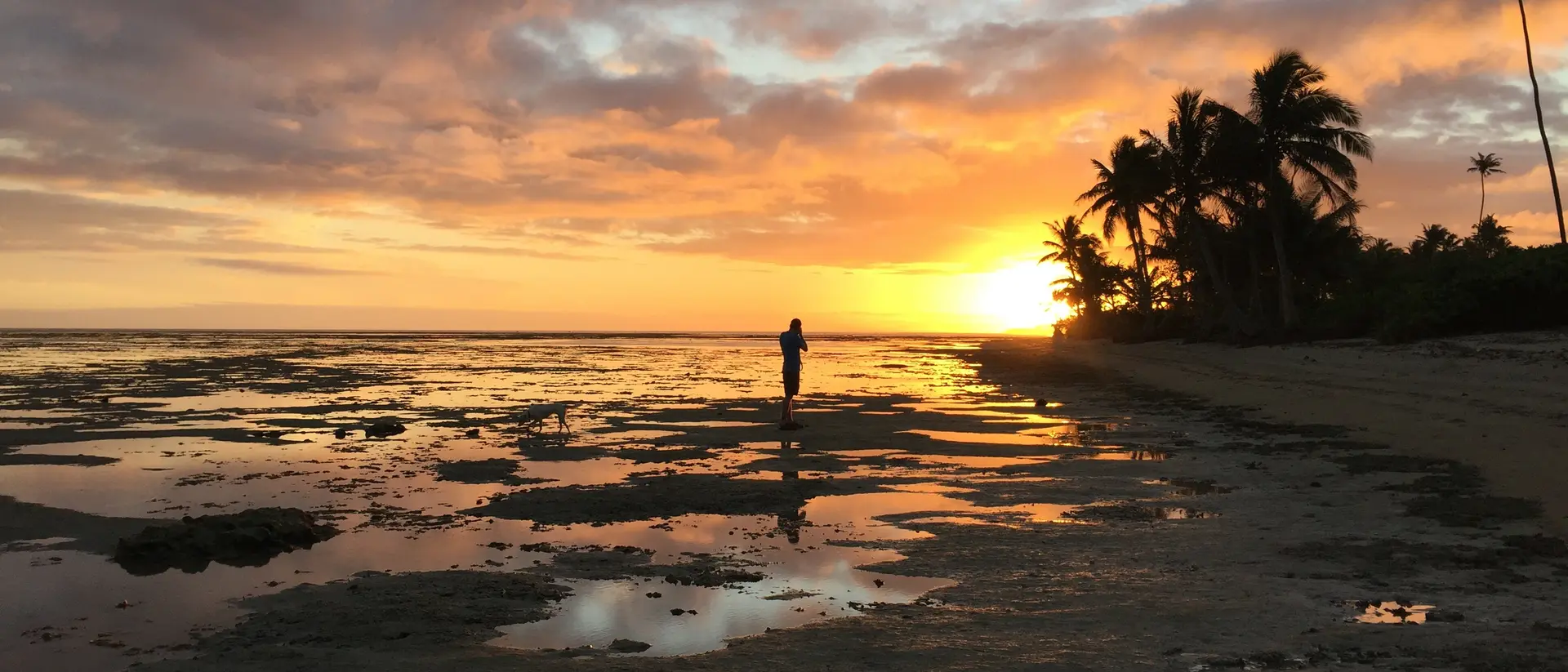 Vanua Levu, Fiji a man walks across the beaches of Vanua Levu, Fji at sunset as the sun is about to dip beneath the horizon