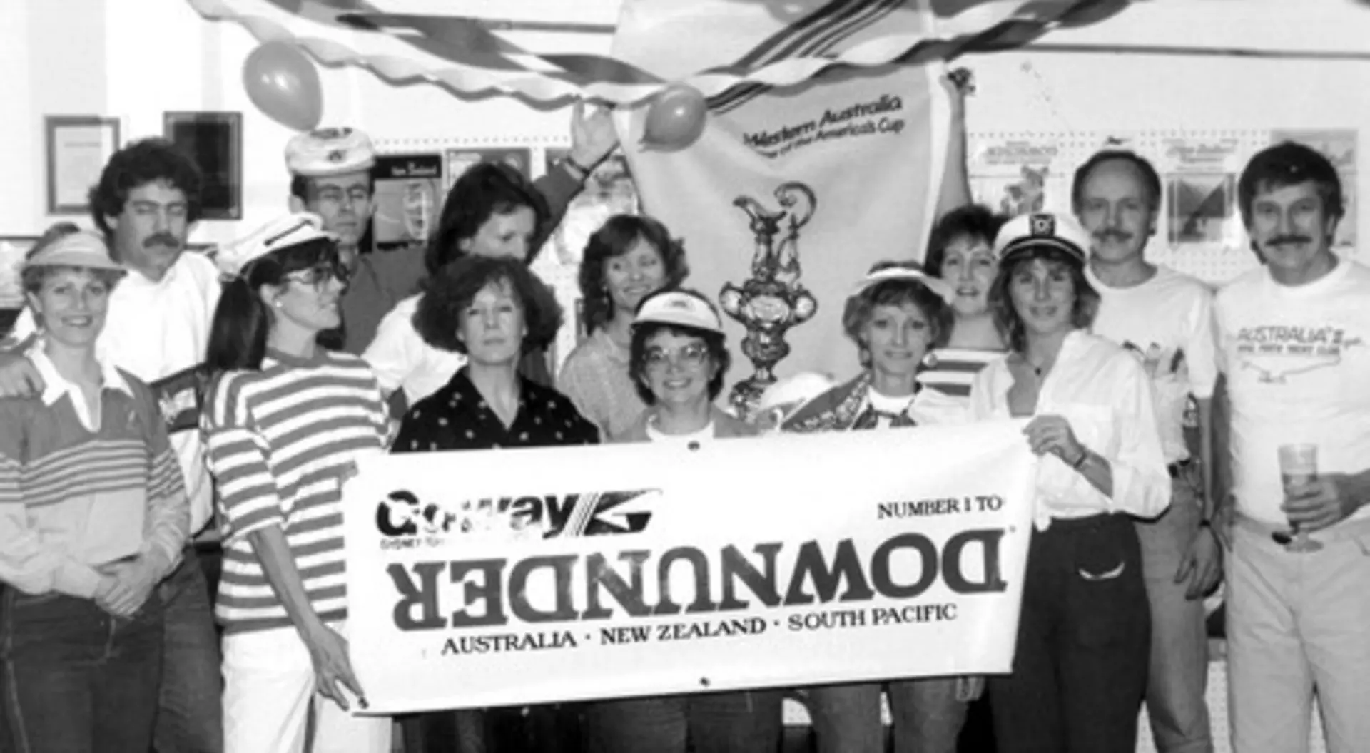 The Goway staff parties in an archival black and white photo of many people holding a sign.