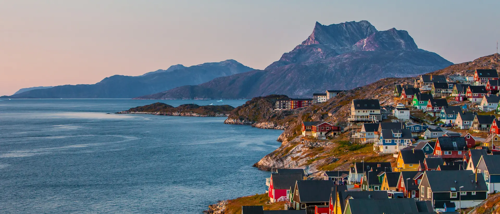Nuuk A coastal view of the Greenlandic capital of Nuuk with its colourful homes lining the edge of the water and backdrop of mountains.