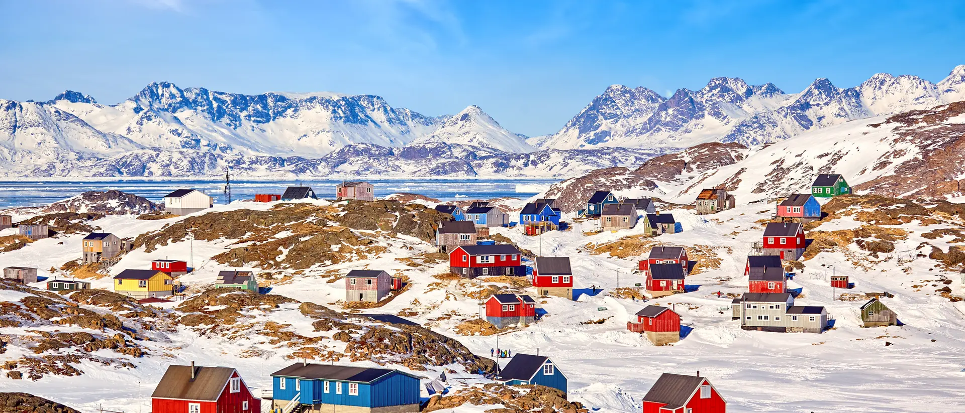 A colourful village in remote Greenland with blue and red houses under a clear and sunny sky in winter