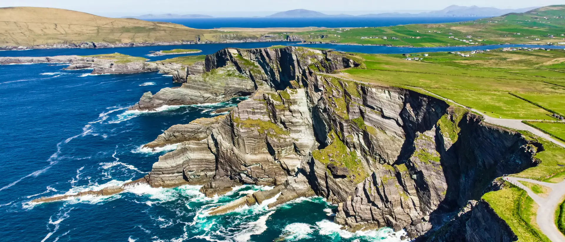 Amazing wave lashed cliffs surrounded be green hills on a sunny day