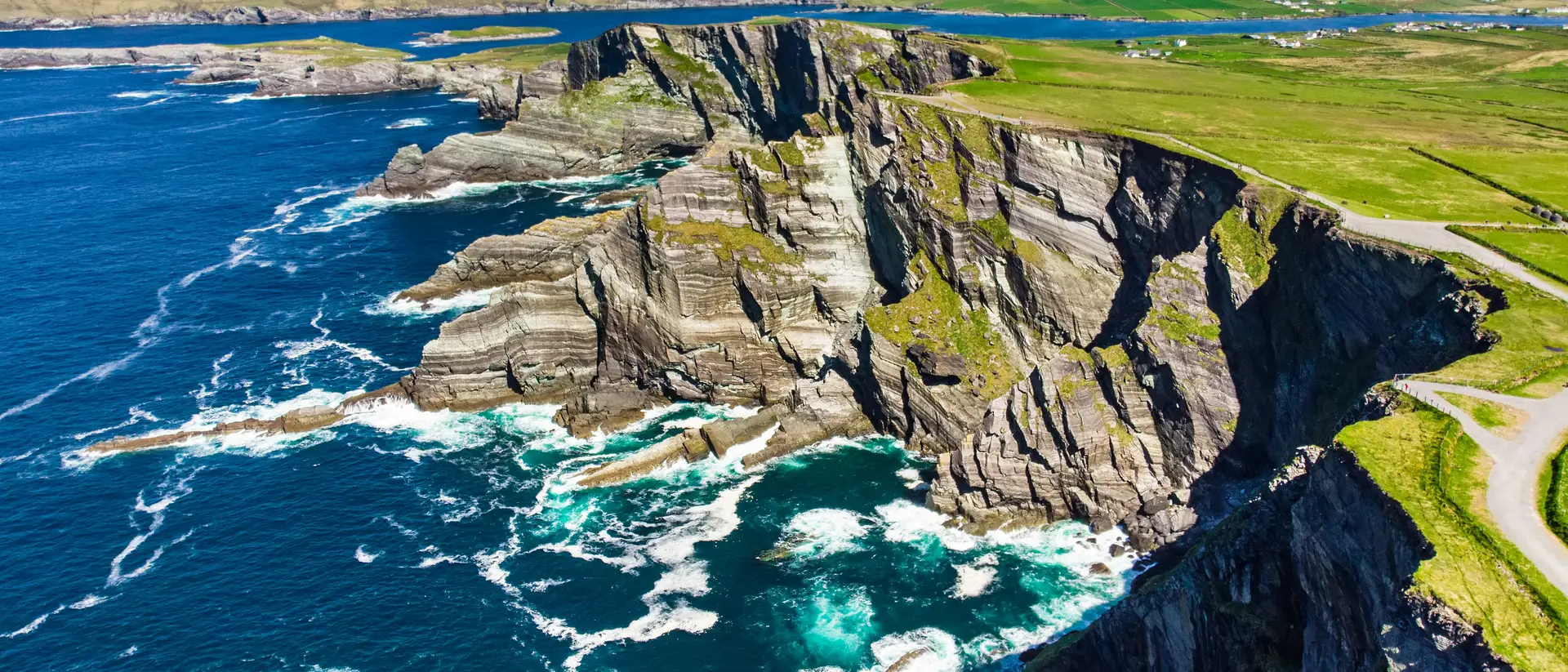 Amazing wave lashed cliffs surrounded be green hills on a sunny day
