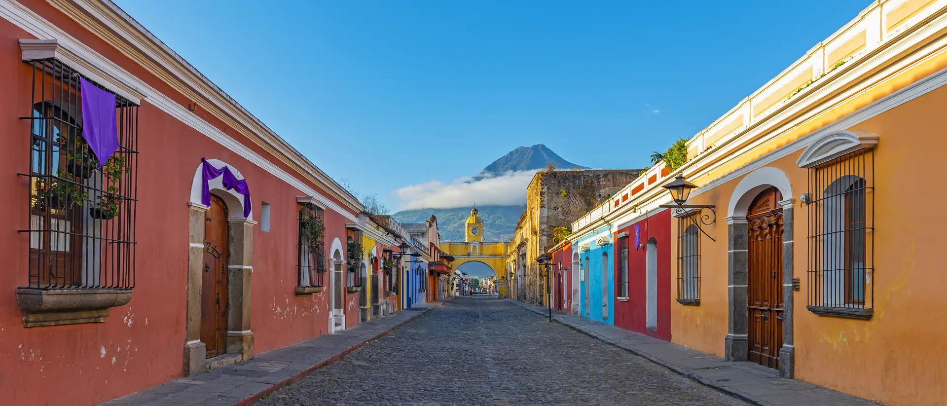 Antigua, Sacatepéquez "Colorful main street of Antigua city at sunrise with the famous yellow arch and the Agua volcano in the background "