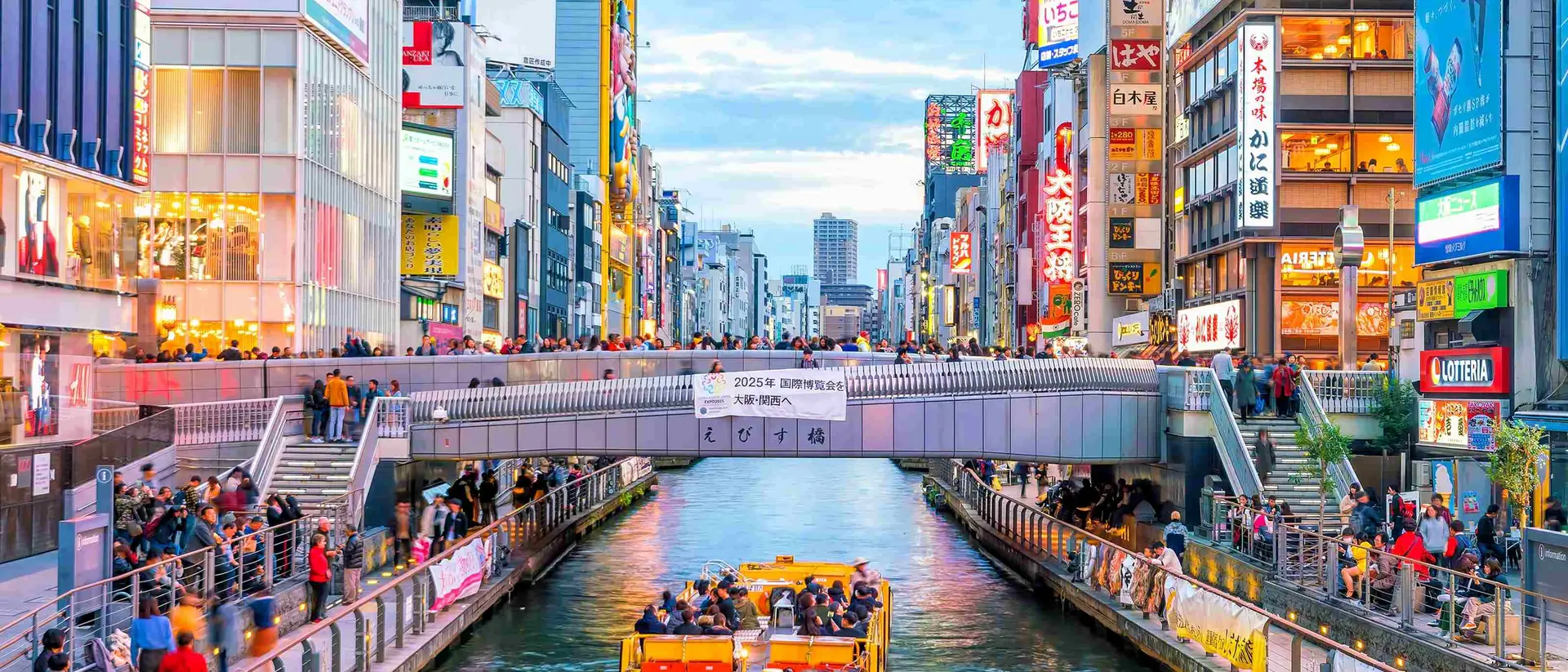 Boat floating down canal on Dotonbori shopping street, a famous destination for traveling and shopping in Osaka
