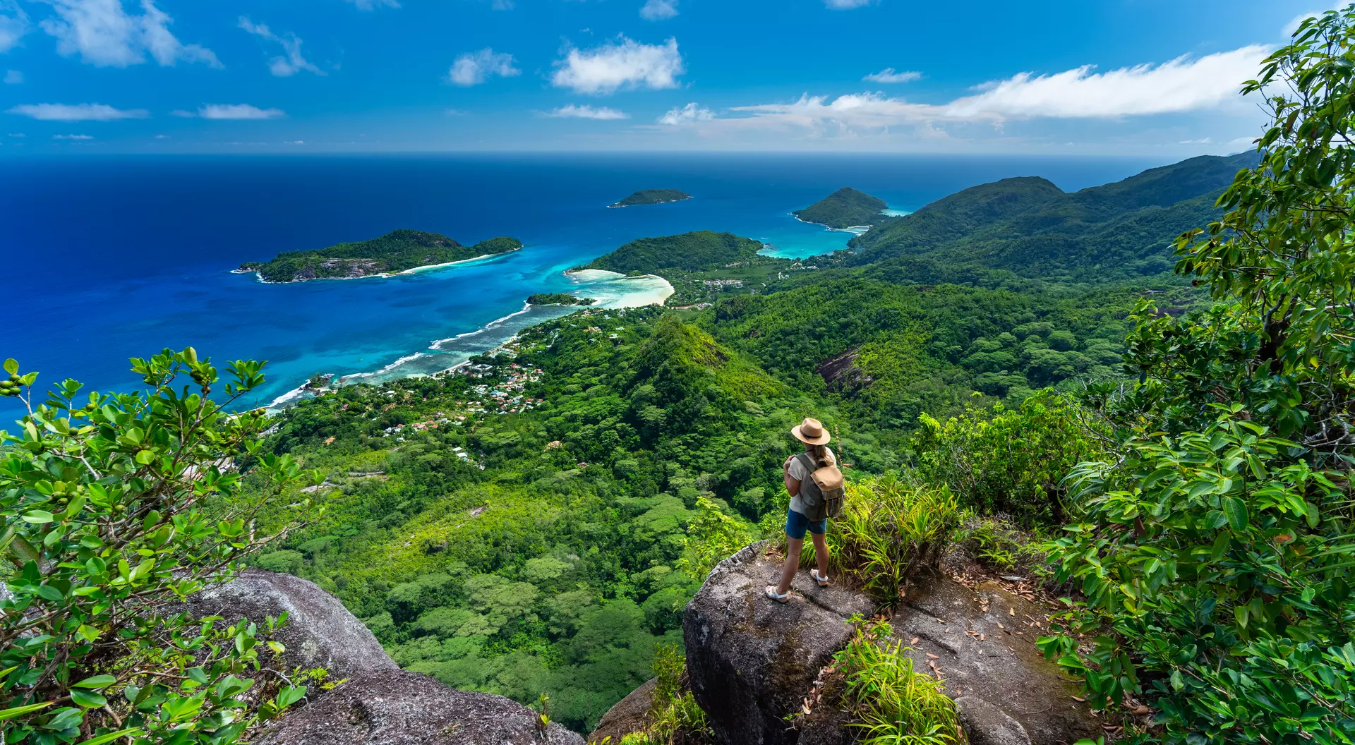 Woman hiker standing high above indian ocean on tropical island of seychelles mahe enjoying amazing view