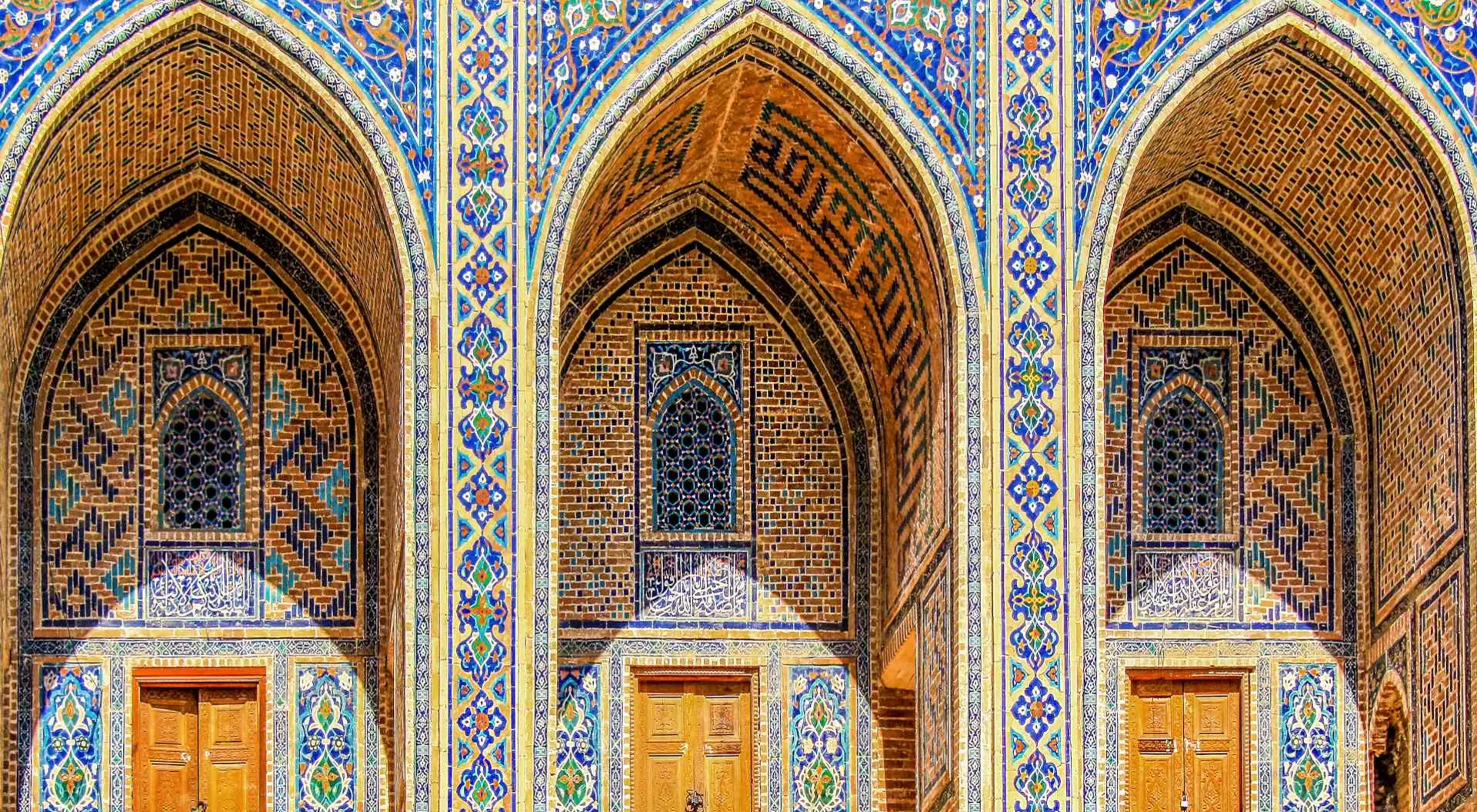 Sherdor Madrassah facade with blue, yellow and green tiles, wall with tall arches and windows