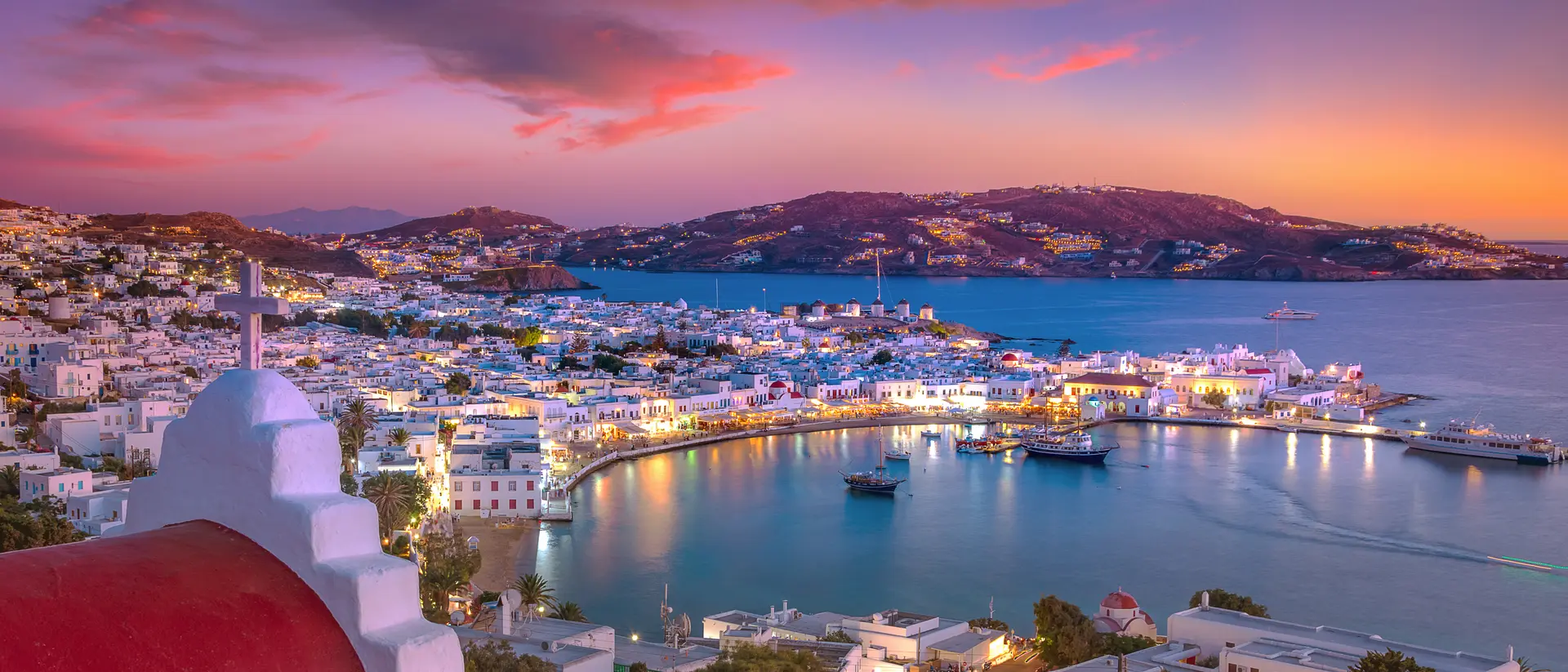 Mykonos port with boats and windmills at evening