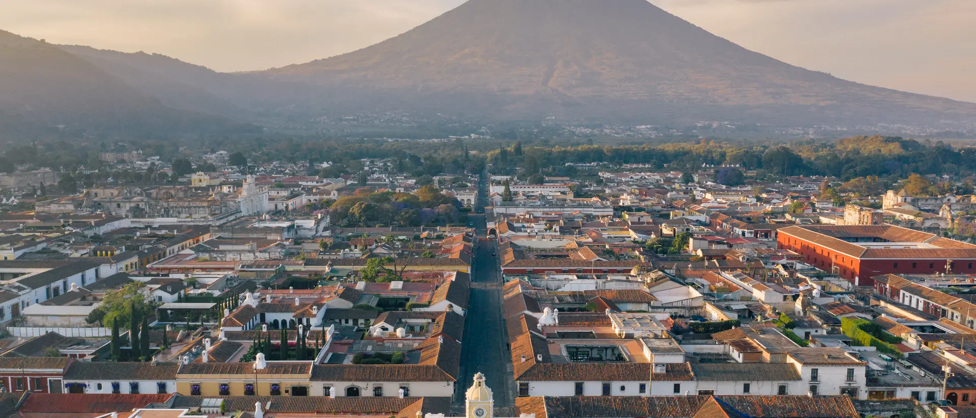 Areal photo of the historic old town of Antigua in Guatemala, surrounded by their active volcanos.