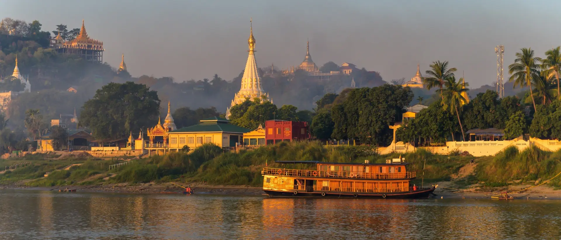 Irrawaddy River Landscape of Myanmar from the river just after sunrise. Warm colors, lots of pagoda's and a steamboat