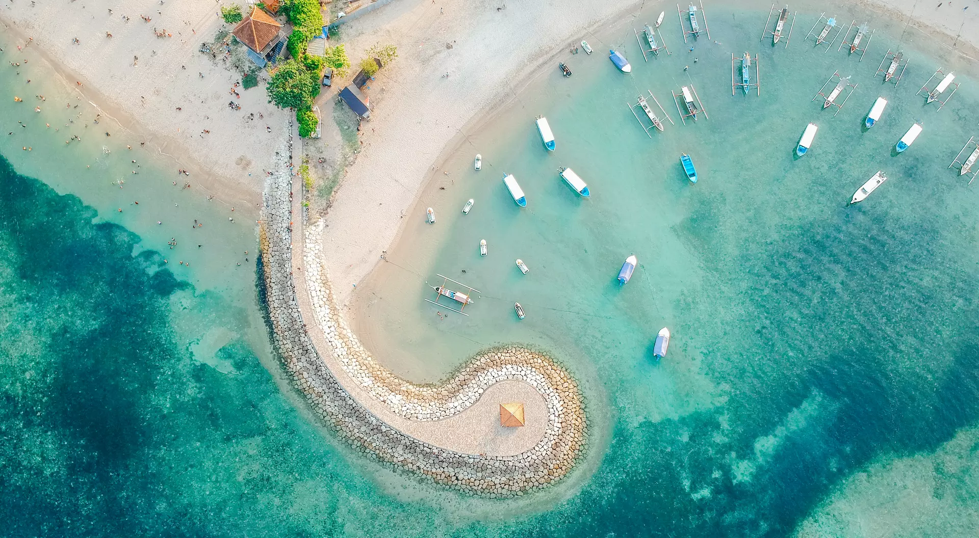 Aerial drone view of ocean, traditional Balinese boats, beach, shore on Sanur Beach, Bali
