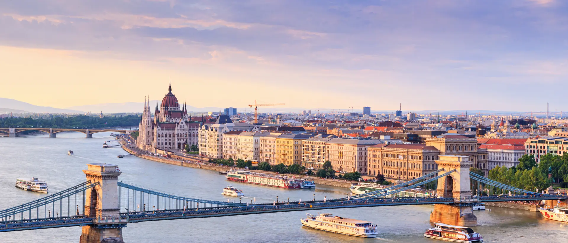 A panoramic view of Budapest, featuring the Chain Bridge and the Hungarian Parliament Building beside the Danube River.