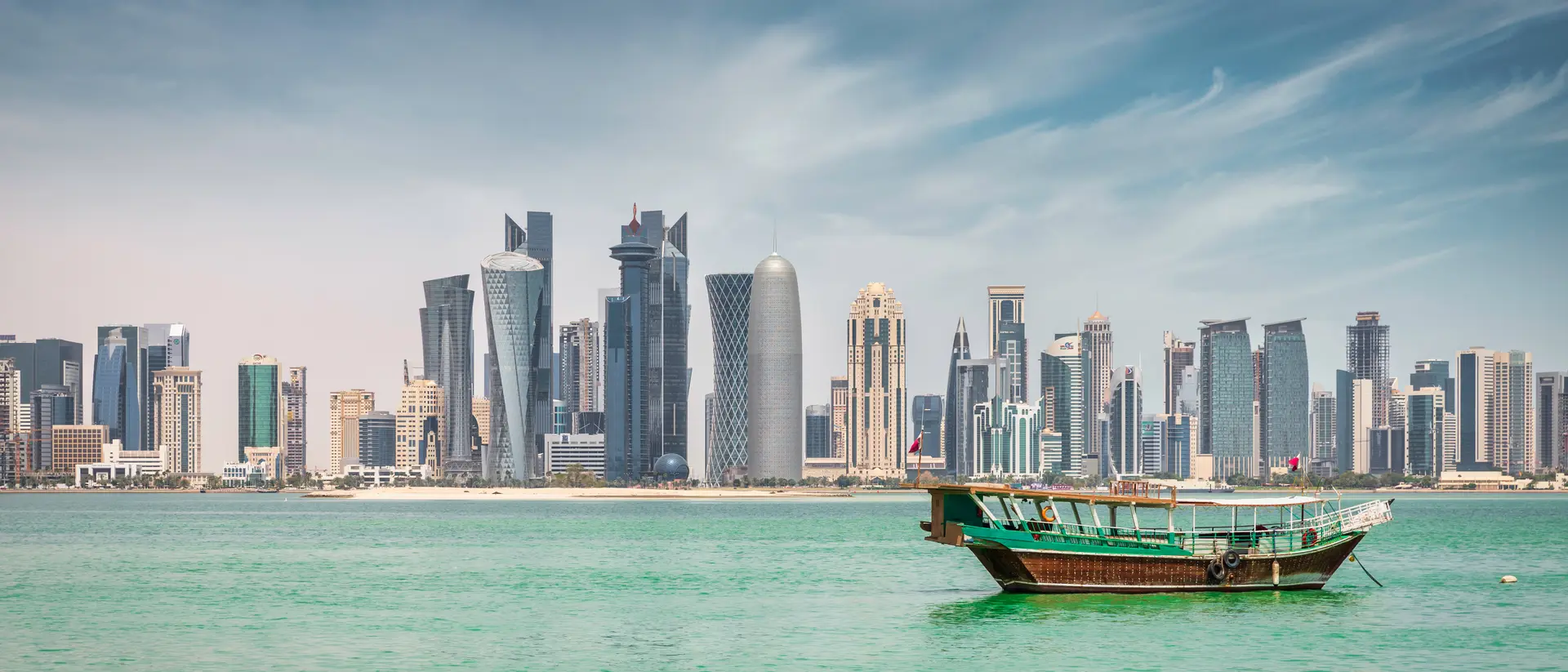 Corniche Promenade Waterfront panorama at Doha Corniche Promenade with anchored typical qatari Dhow Cruise Boat