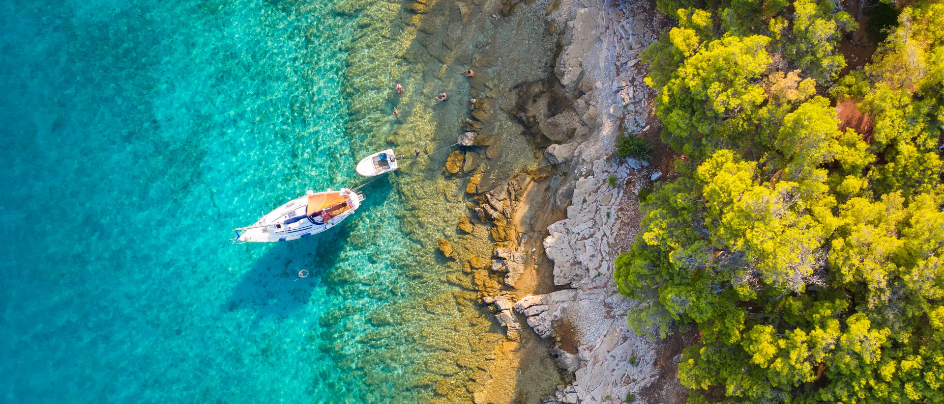 Hvar Island A small sailing boat is moored next to the shore which is covered with a lush pine forest in Hvar