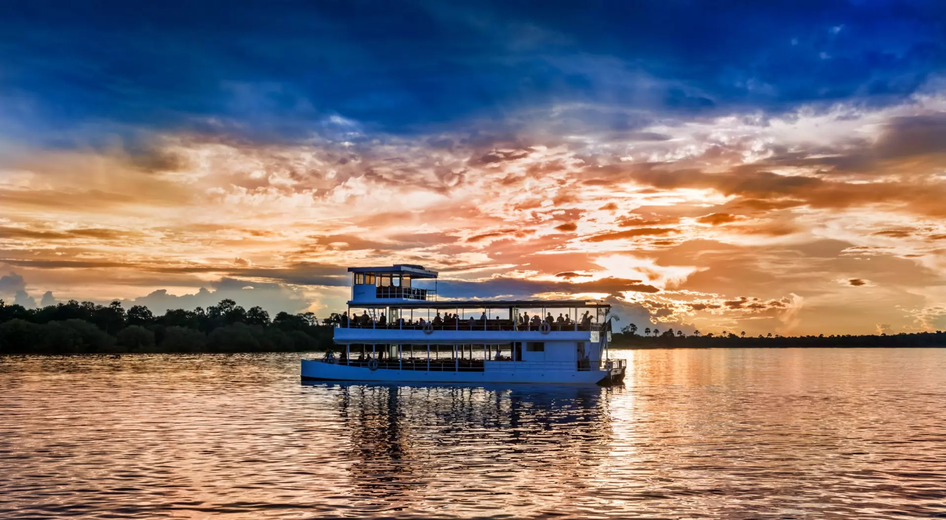 Zambezi River, Livingstone, Zambia Picturesque sunset landscape with the riverboat at Zambezi river